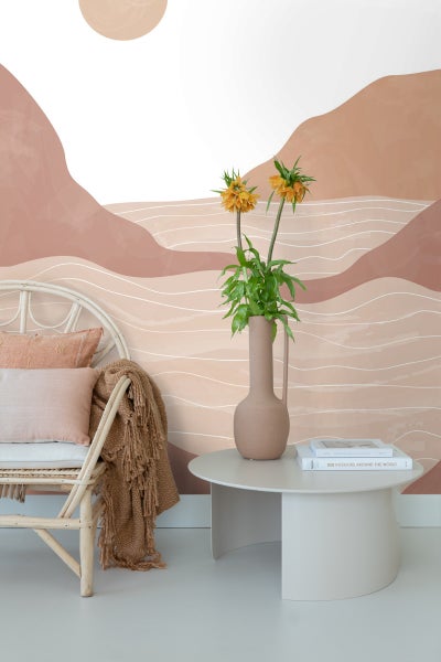 Wohnraum mit Grafik Wandbild, Rattansessel, Kissen, Decke, Beistelltisch und Blumen in Vase