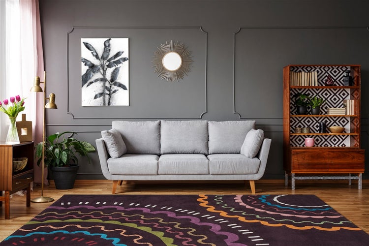 Wohnzimmer mit grauem Sofa, gemustertem Teppich, Holzregal, Wandspiegel und Dekoration im modernen Stil.