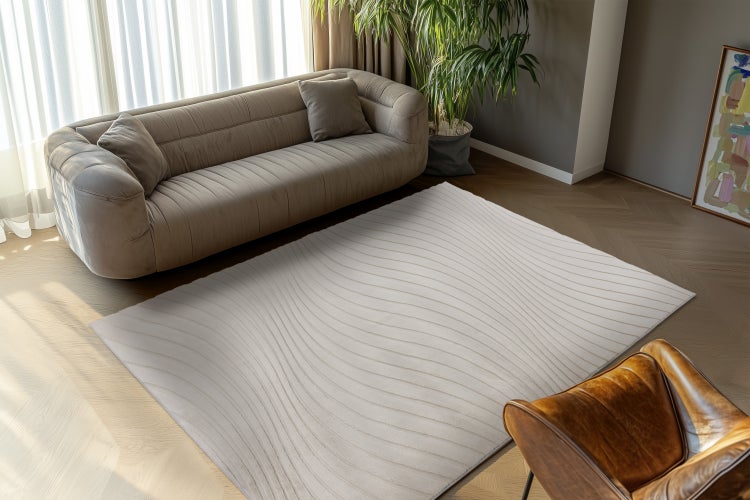 Wohnzimmer mit modernem Sofa und rechteckigem Teppich mit Wellenmuster auf Parkettboden.
