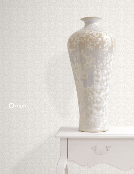 Dekorative Vase auf einem Tisch vor einer gemusterten Tapete