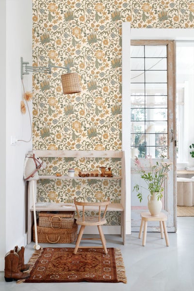 Ein Raum mit floral gemusterter Tapete, einem Holzregal mit Spielzeug, einem Holzstuhl und einem kleinen Teppich auf dem Boden.