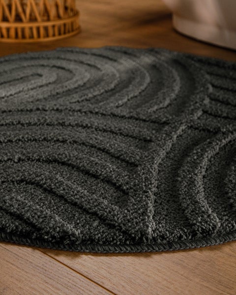 Runder Badeteppich mit Hoch-Tief-Struktur und Wellenmuster in Anthrazit.