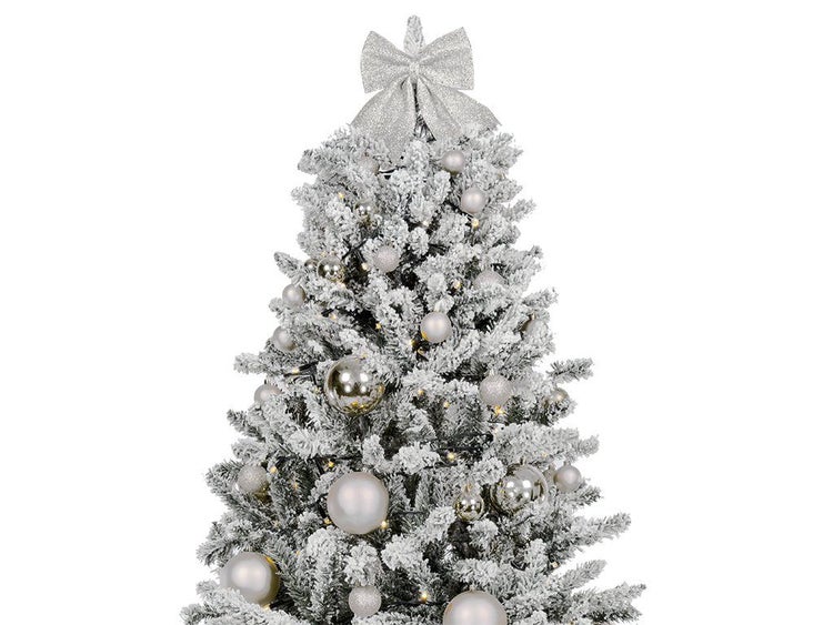Künstlicher, verschneiter Weihnachtsbaum mit Beleuchtung, glänzenden Weihnachtskugeln und einer großen Schleife als Baumspitze.