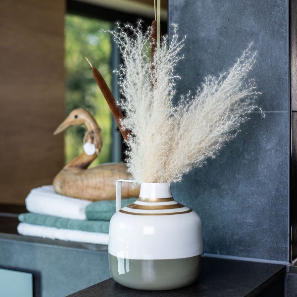 Dekorative Szene mit Vase, Schilfgras und Holzente im Badezimmer