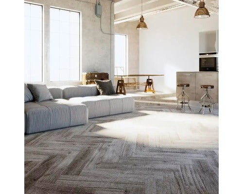 Großzügiges Wohnzimmer im Industriestil mit grauem Modulsofa und Bodenbelag in Holzoptik im Fischgrätmuster.