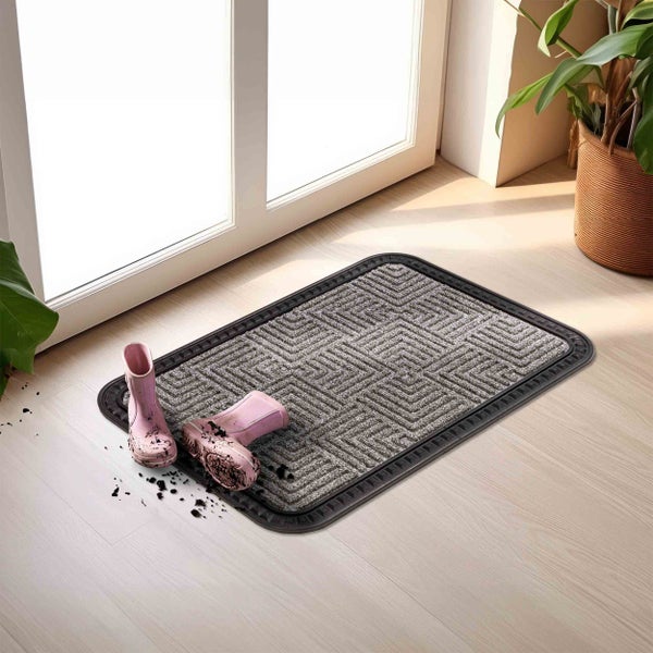 Schmutzfangmatte mit Muster und Paar Gummistiefel darauf vor einer Tür