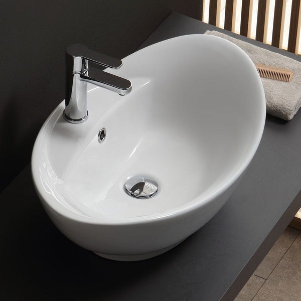 Ovales Aufsatzwaschbecken aus Keramik mit verchromter Armatur und Überlauf auf einer Waschtischplatte im modernen Badezimmer.