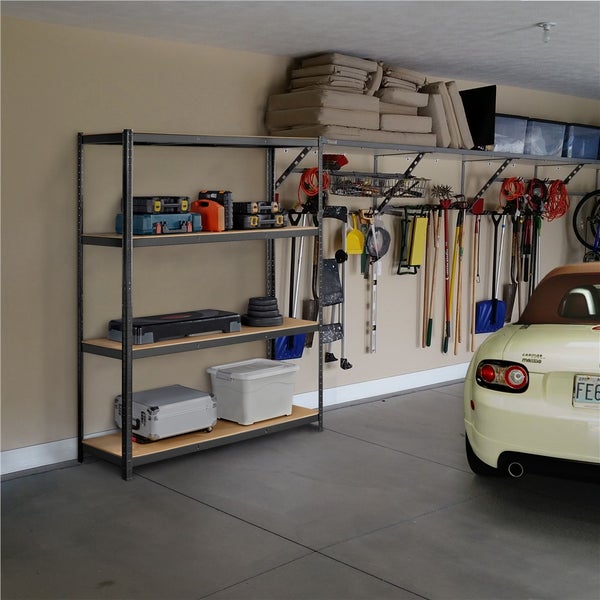 Aufgeräumte Garage mit einem Schwerlastregal aus Metall und Holz sowie einem Wandschienensystem für Gartenwerkzeuge und Werkzeugkoffer.
