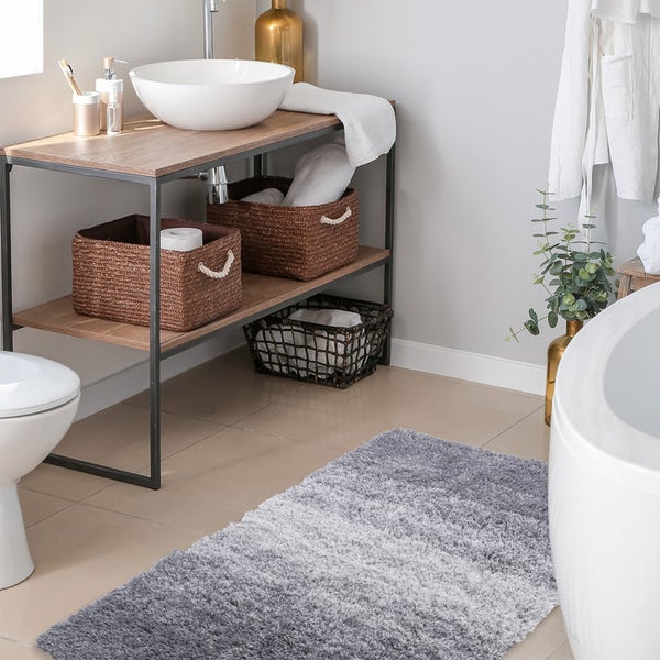 Badezimmeransicht mit Waschtisch, Körben und Badematte