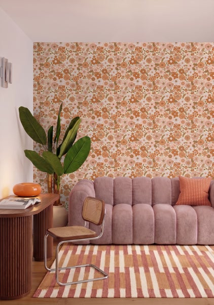 Retro-Blumen-Tapete in einem hellen Wohnzimmer mit geripptem Sofa, einem Holzschreibtisch und einem gestreiften Teppich.