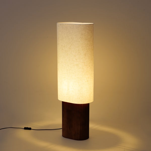 Moderne Tischleuchte mit ovalem Textilschirm und geripptem Holzfuß, strahlt warmes Licht aus.