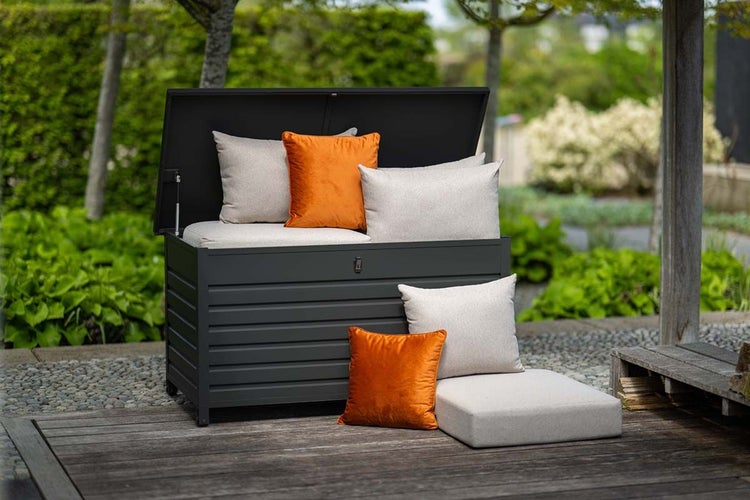 Gartenbox aus Metall in Anthrazit mit geöffnetem Deckel und Gartenkissen auf einer Holzterrasse im Außenbereich.