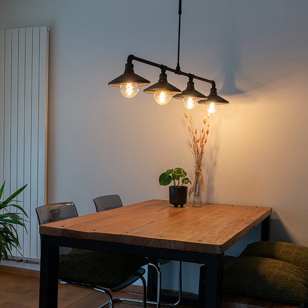 Esszimmer mit Holztisch und einer schwarzen Pendelleuchte mit vier Lampen
