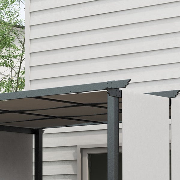 Pergola mit grauem Metallrahmen und beigen, verschiebbaren Stoffbahnen vor einer Hausfassade mit weißem Profilholz.
