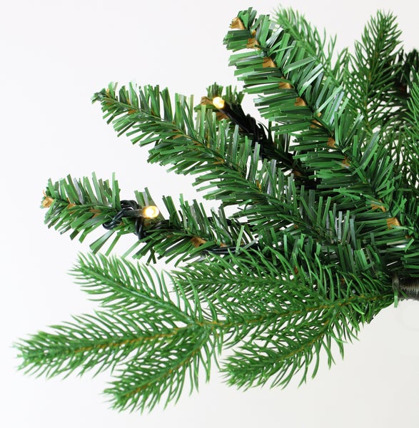 Detailaufnahme eines grünen künstlichen Weihnachtsbaumzweigs mit kleinen Lichtern