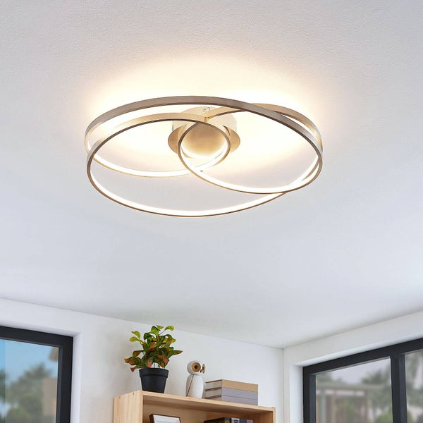 Moderne LED-Deckenleuchte mit drei ineinander verschlungenen Ringen aus Metall an einer hellen Zimmerdecke.