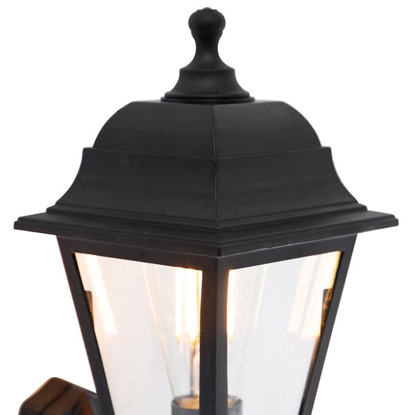 Schwarze Außenwandleuchte im Laternen-Stil mit abgestuftem Dach und Glaseinsätzen, inklusive Filament-Leuchtmittel.