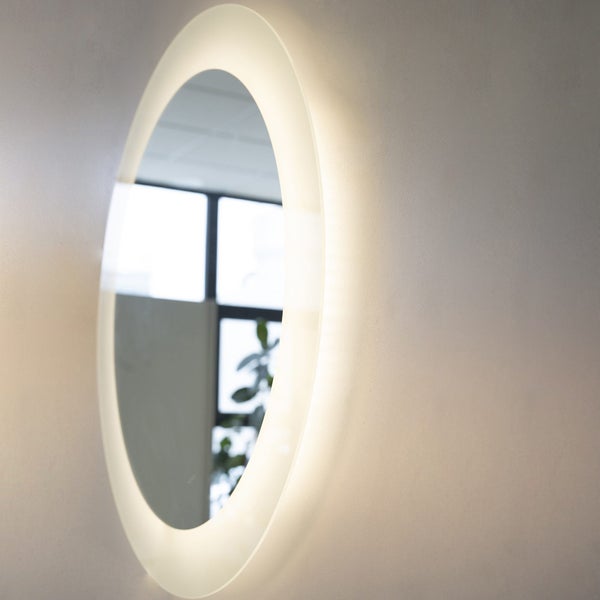 Runder Badezimmerspiegel mit integrierter LED-Beleuchtung und Hintergrundbeleuchtung an einer Wand.