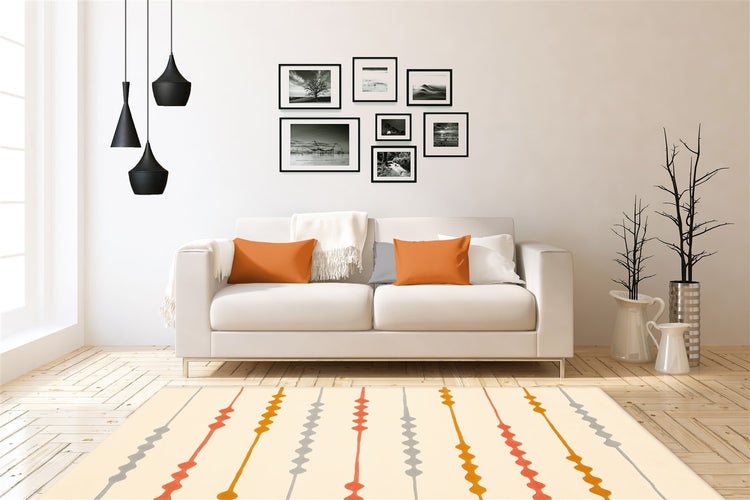 Wohnzimmer mit Sofa, Bildergalerie an der Wand, drei Hängeleuchten und einem Teppich mit geometrischem Streifenmuster auf Holzboden.