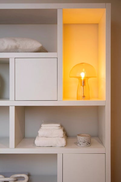 Regal mit Handtüchern, Kissen, Dekorationsgegenstand und einer Lampe