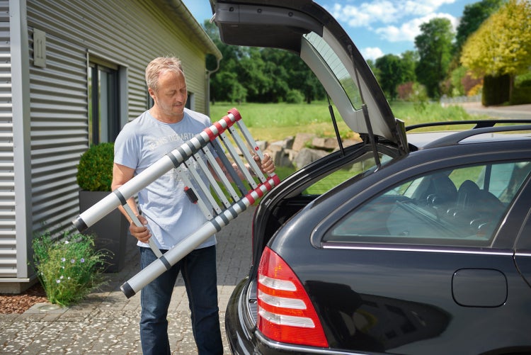 Mann verstaut Mehrzweckleiter im Kofferraum eines Autos