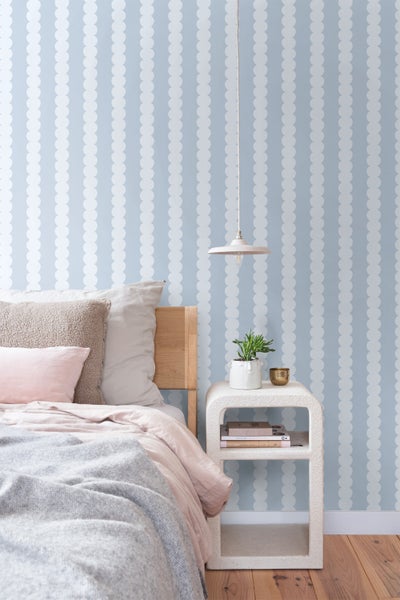 Schlafzimmer mit Bett, Nachttisch und Wandtapete mit Punktmuster