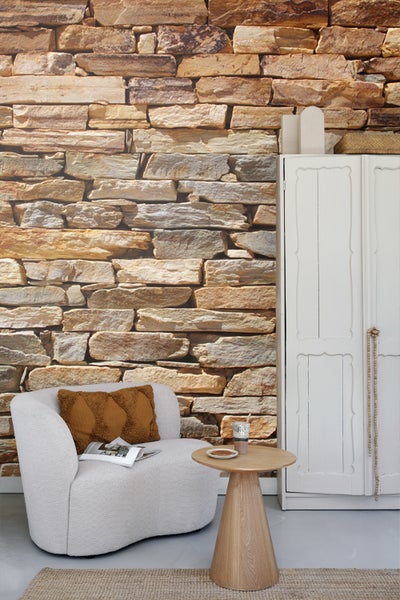 Wohnzimmer mit Sessel, Beistelltisch und Wand in Steinoptik