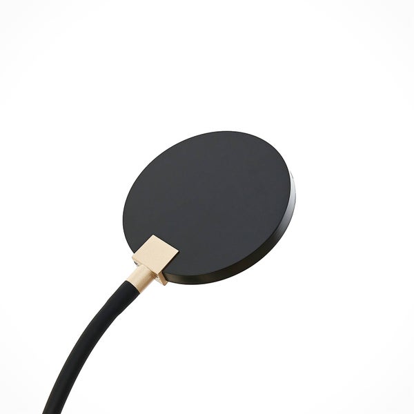 Detailansicht eines schwarzen, runden Lampenkopfs mit schwarzem flexiblem Arm und einem goldfarbenen Verbindungselement aus Metall.