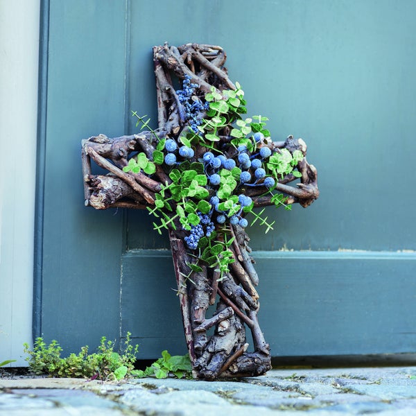 Kreuz aus Zweigen mit Beeren und Blättern vor einer Tür