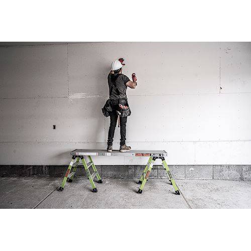 Handwerker mit Schutzhelm steht auf einer Arbeitsplattform Little Giant Plank für Arbeiten an der Wand.