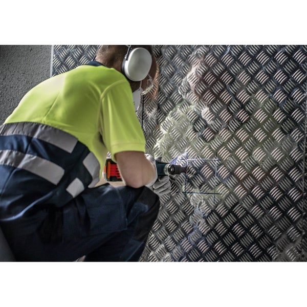 Handwerker schneidet mit einem Multifunktionswerkzeug ein Loch in eine Riffelblechwand.