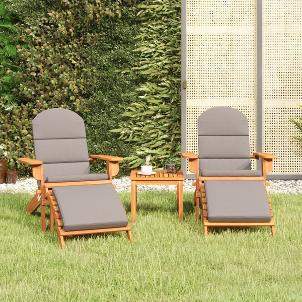 Zwei Liegestühle mit Fußstütze und kleinem Tisch im Garten.