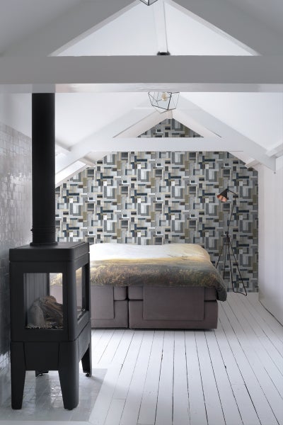 Schlafzimmer mit Kaminofen, Bett und gemusterter Tapete im Dachgeschoss