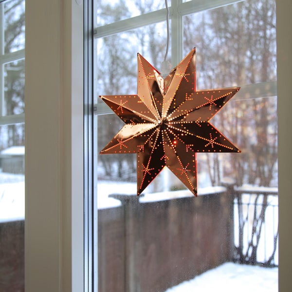 Dekorativer, beleuchteter Weihnachtsstern vor einem Fenster