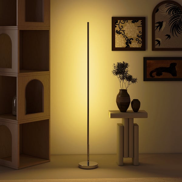 Minimalistische schwarze LED-Stehleuchte in einem modernen Wohnzimmer mit Holzregal, Beistelltisch und Wandbildern, die warmes Licht abstrahlt.