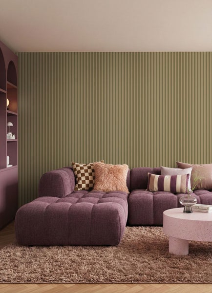 Wohnzimmer mit lila Ecksofa, Teppich und gestreifter Tapete