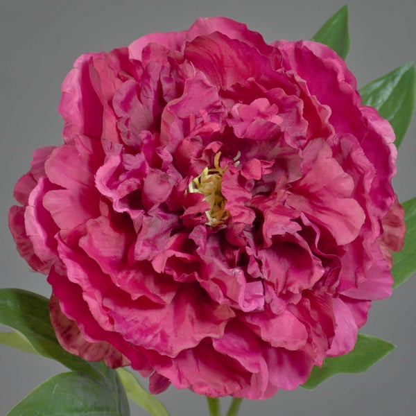 Künstliche Pfingstrose in dunklem Pink mit grünen Blättern.