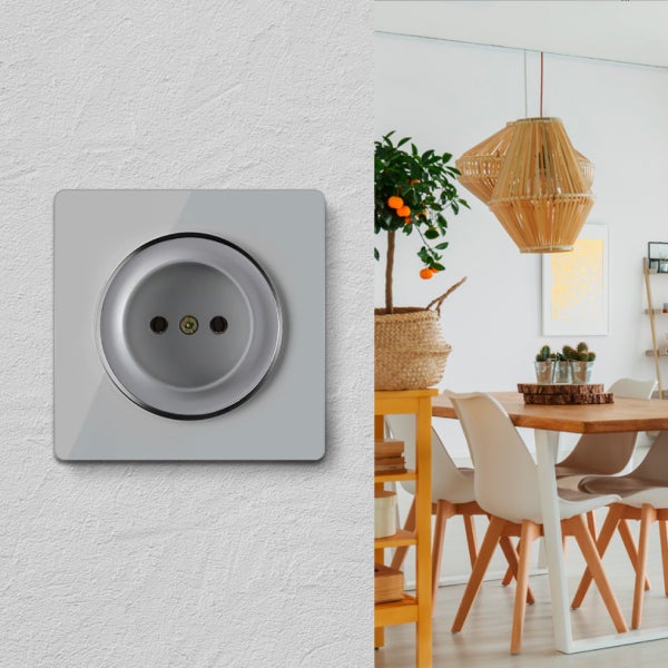 Moderne Steckdose mit quadratischer Abdeckung montiert an einer hellen Wand, daneben ein heller, wohnlich gestalteter Essbereich.