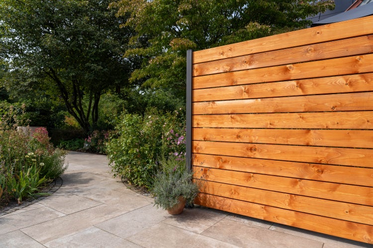 Holzzaun im Gartenbereich mit Steinweg und Bepflanzung
