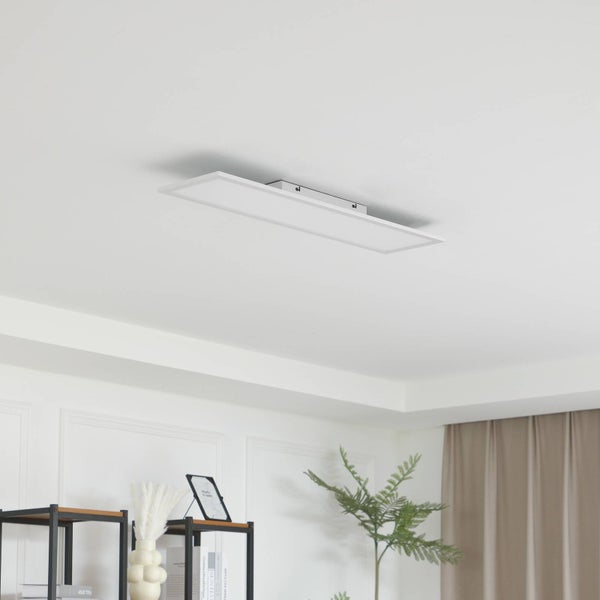 Modernes, rechteckiges LED-Panel als Deckenleuchte in einem hellen, minimalistischen Raum mit Decke, Regal, Pflanze und Vorhang.