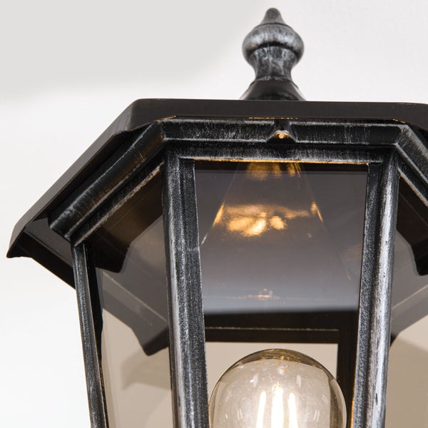 Außenleuchte in Laternenform aus Metall und Glas mit sichtbarem Leuchtmittel.