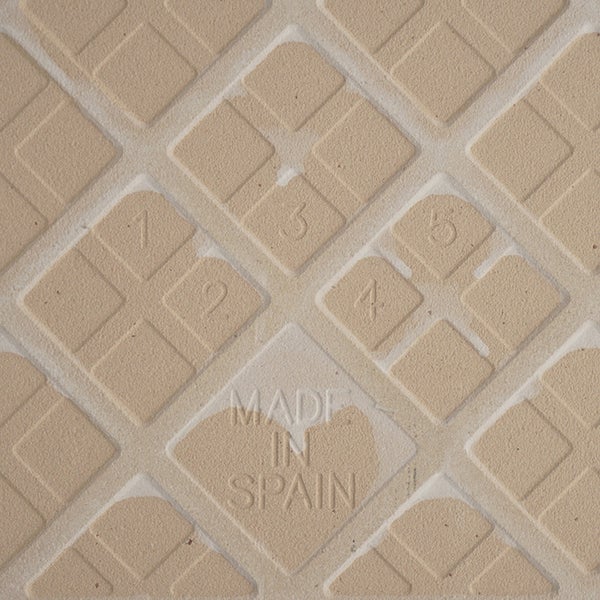 Rückseite einer Wandfliese mit Prägung Made in Spain und einem geometrischen Muster für bessere Haftung