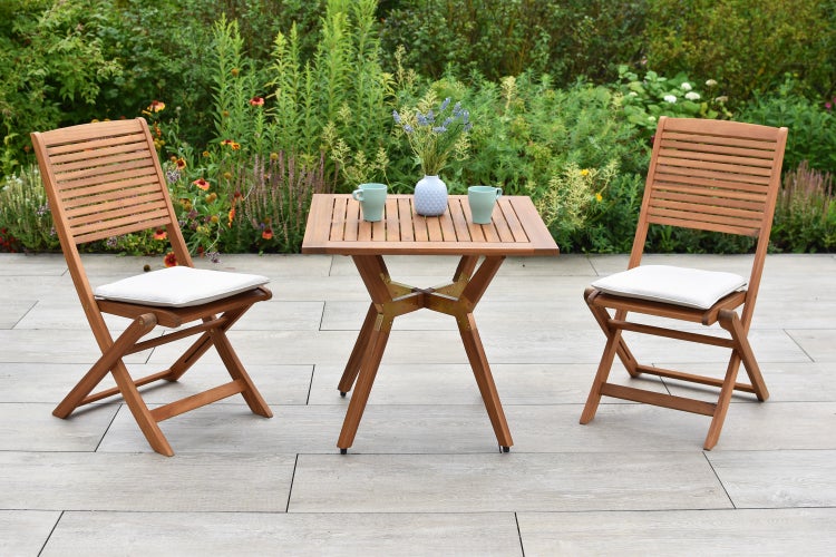 Quadratischer Gartentisch mit zwei Klappstühlen und Kissen im Außenbereich