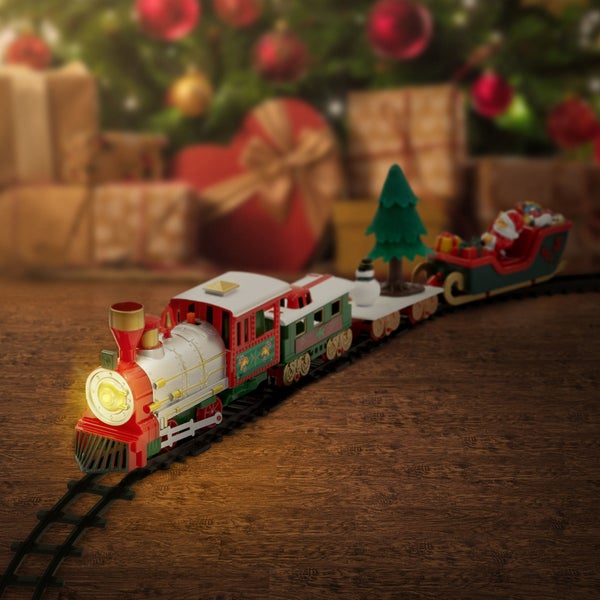 Weihnachtszug Spielzeug auf Schienen mit leuchtender Lokomotive und Anhängern vor einem geschmückten Weihnachtsbaum mit Geschenken.