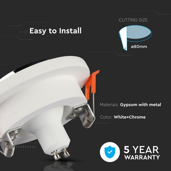 Moderne runde Feuerschale aus Beton auf einer Terrasse mit Steinplatten vor einer Holzwand mit brennender Flamme.