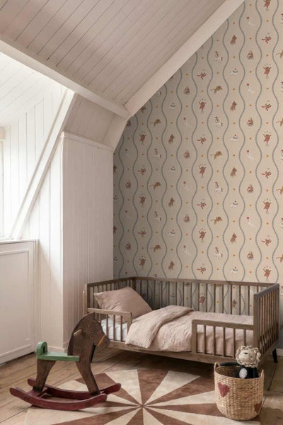 Kindertapete mit Zirkusmotiven wie Akrobatik-Hunden und Affen in einem hellen Kinderzimmer mit Holzbett und Schaukelpferd.