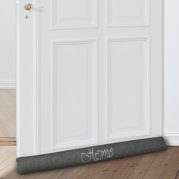 Türluftstopper aus Stoff mit der Aufschrift Zuhause vor einer Tür
