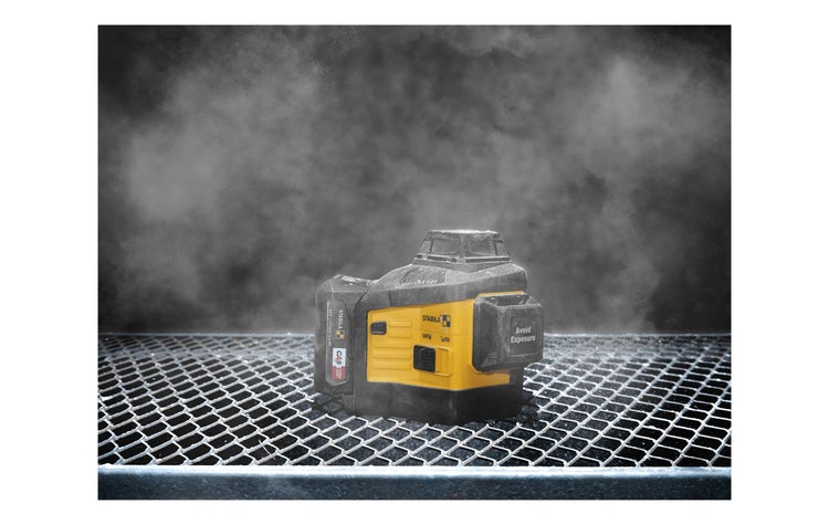 Stabila Multilinien-Laser LAX 600 auf einem Metallgitter in einer staubigen Umgebung auf der Baustelle.