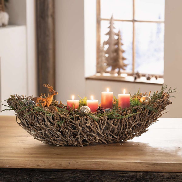 Adventskranz mit Kerzen, Dekoration und hölzernem Hirsch auf einem Holztisch.