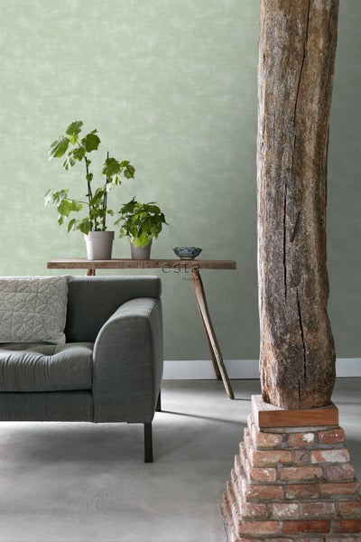 Wohnraum mit Sofa, Holztisch, Pflanzen und dekorativem Holzpfeiler auf Ziegelsteinsockel